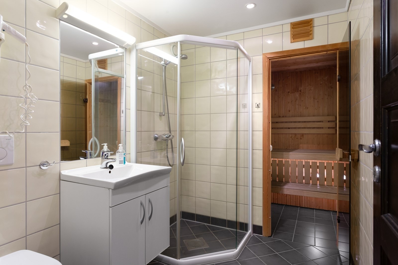 Flislagt bad med gulvvarme, veggmontert toalett og dusjhjørne. Fra badet er det inngang til egen badstue. Galleribilde