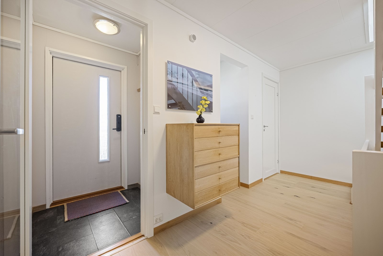 Lys og innbydende entré som leder videre inn i boligens første etasje. Galleribilde