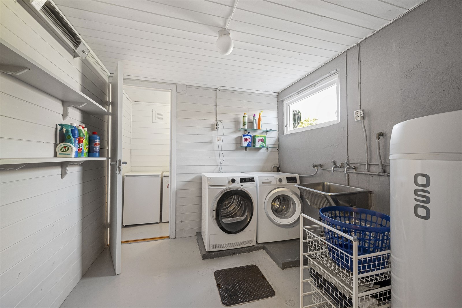 Separat vaskerom i kjelleren med opplegg for vaskemaskin og en nyere varmtvannsbereder. Galleribilde