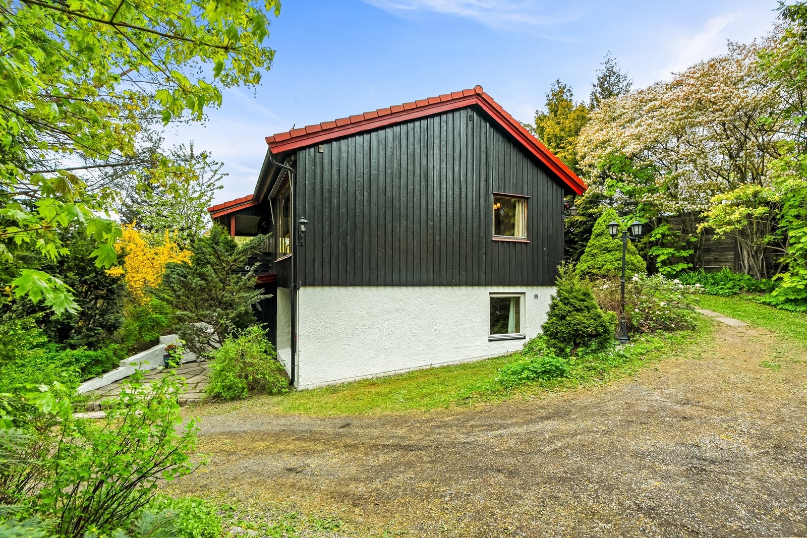Boligen har to innganger og stor gårdsplass mellom huset og garasjen Galleribilde