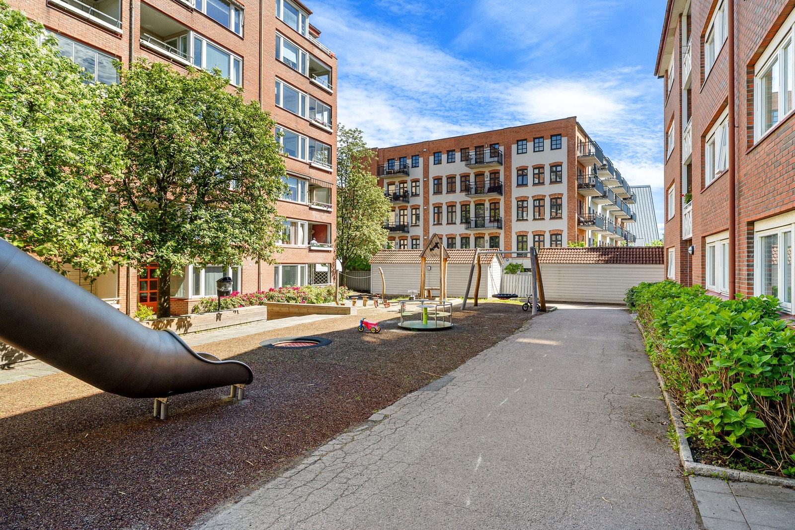 Hyggelig gårdsrom med asfalterte internveier, lekeplass og beplantning. Galleribilde
