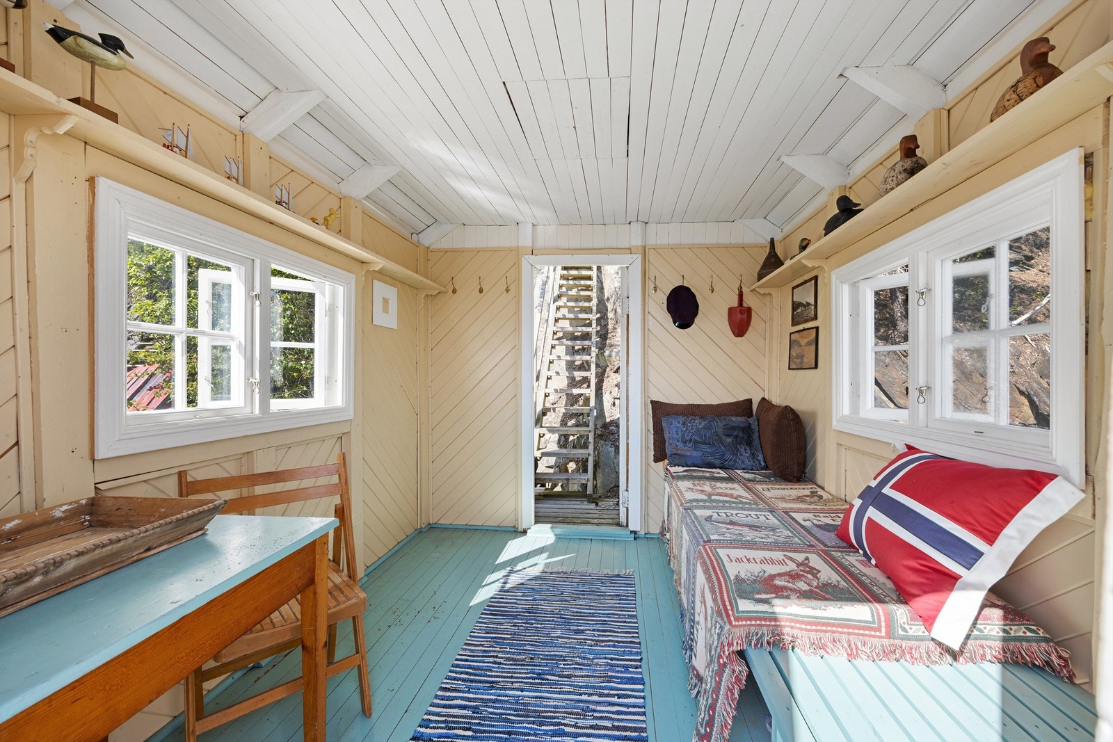 Badehuset er malt innvendig i lyse farger og har vinduer på to sider og dør direkte ut mot vannet. Galleribilde