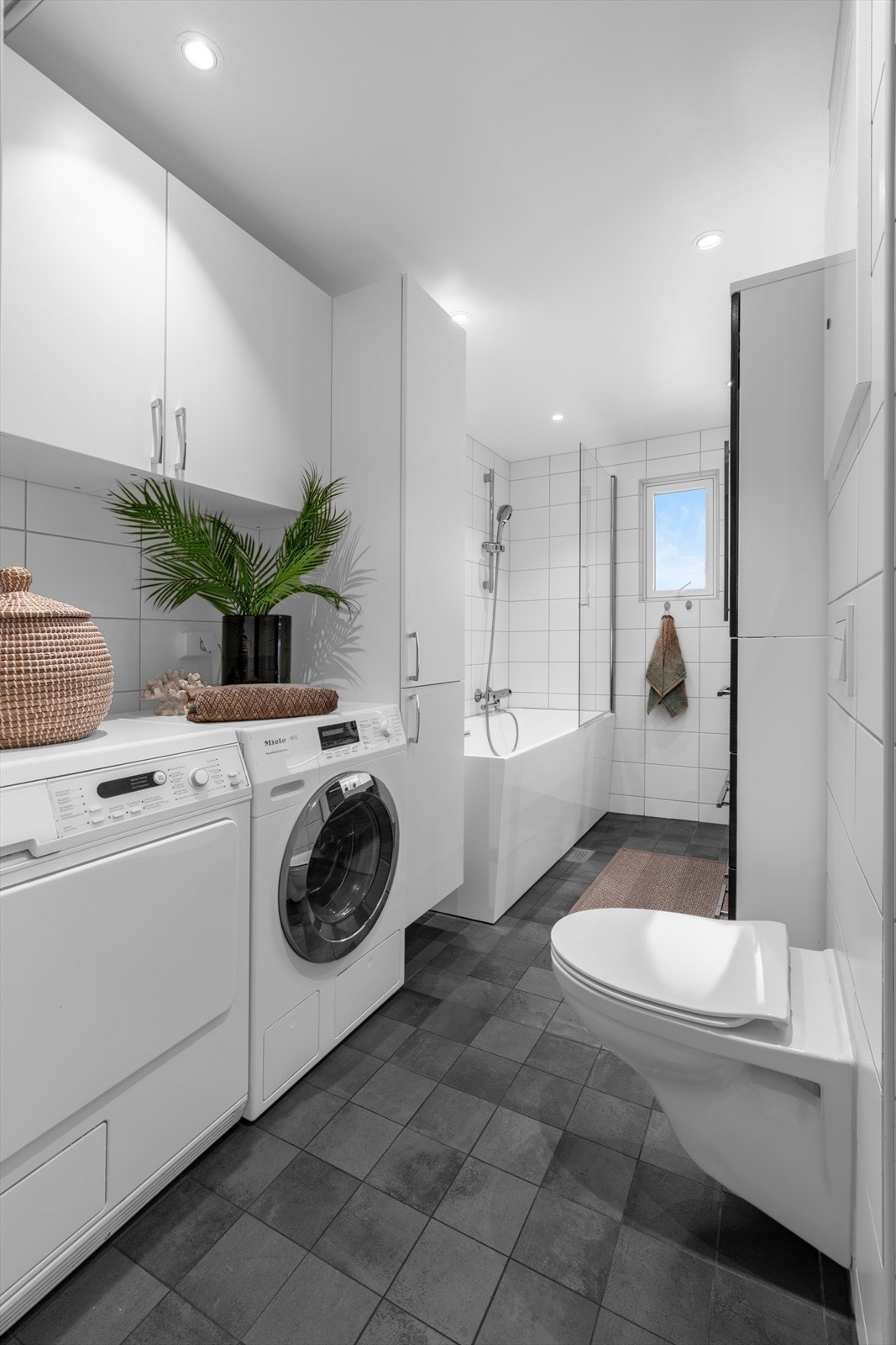 Badet har fliser på vegger og gulv, samt slette himlingsflater og varmekabler i gulv for økt komfort. Galleribilde