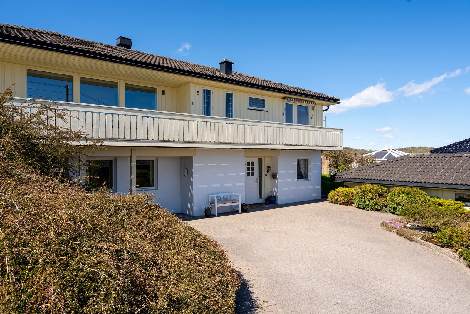 Tomten er opparbeidet med belegningsstein i gårdsplass, blomsterbed, plen og hekk Galleribilde