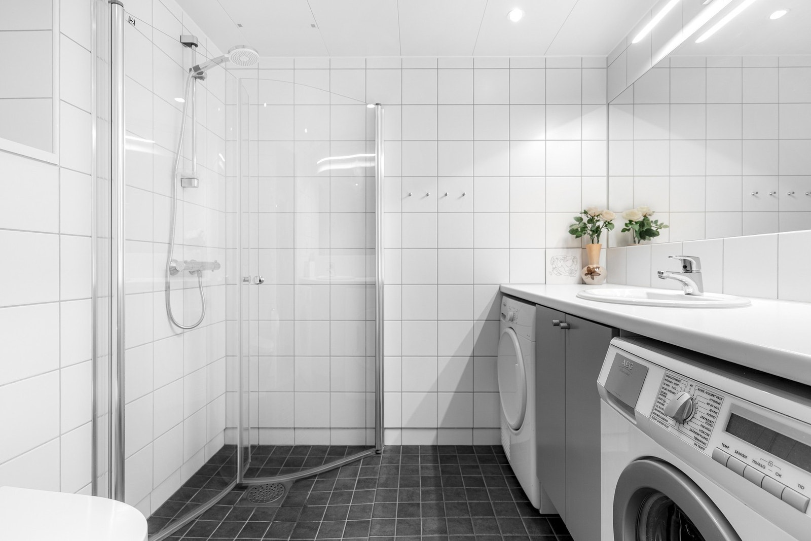 Lyst og moderne baderom fra byggeåret 2008. Baderommet har mørke fliser på gulv med gulvvarme, hvite fliser på veggene, downlights i himlingen og mekanisk avtrekksvifte. Galleribilde