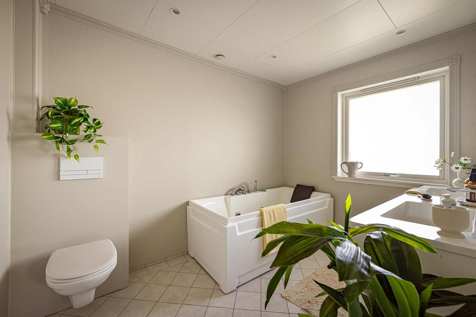 Badet er utstyrt med vegghengt toalett, badekar og baderomsinnredning med nedfelt servant og speil med integrert belysning. Galleribilde