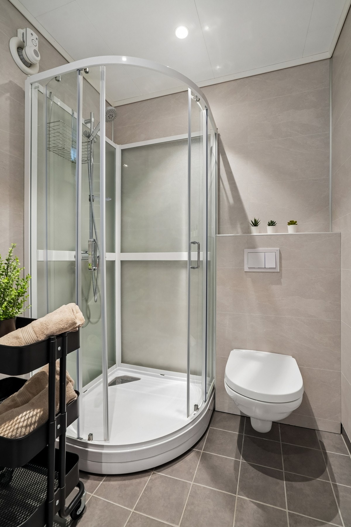 Badet er ellers utstyrt med baderomsmøbel, dusjkabinett og vegghengt toalett. Galleribilde