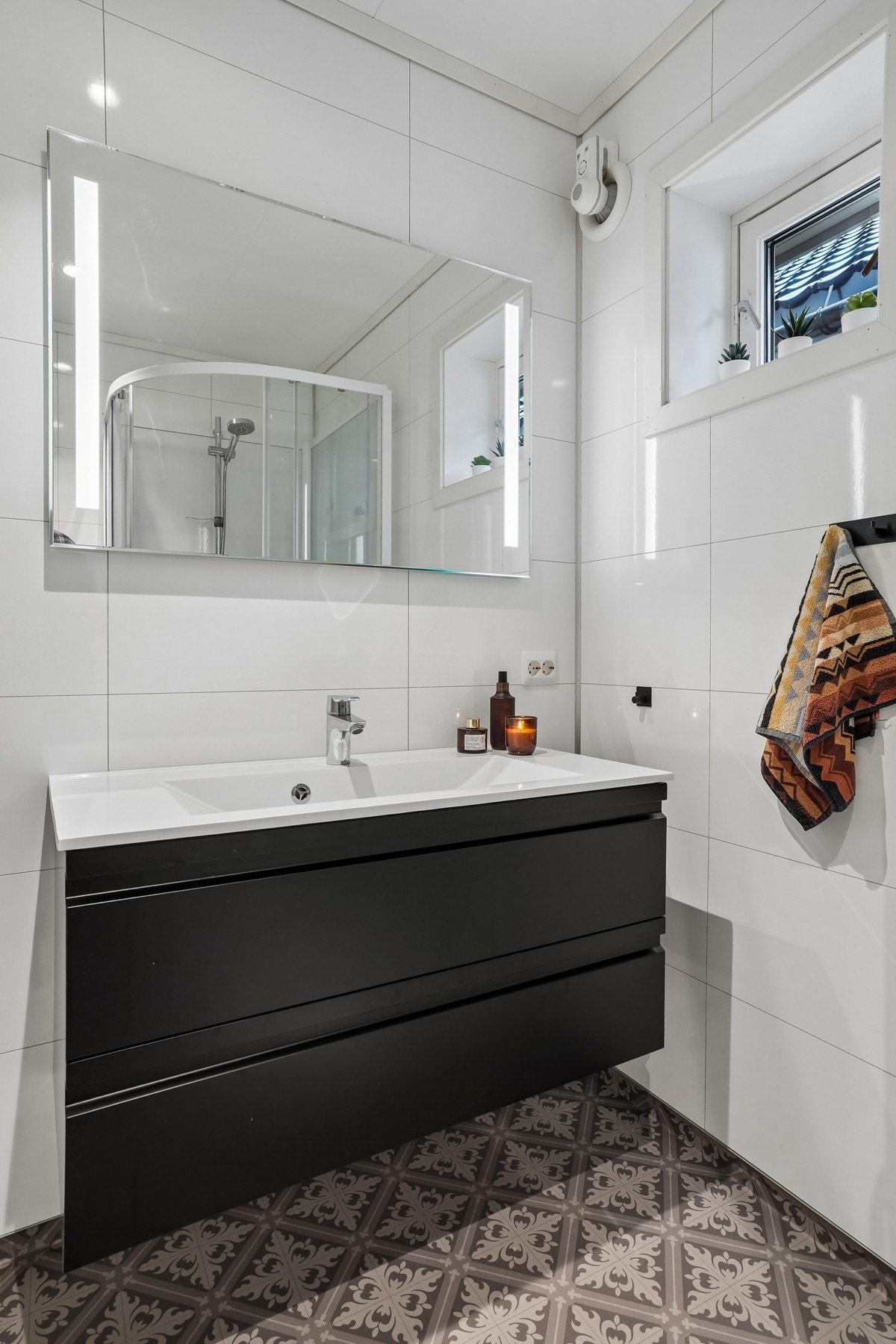 Badet er utstyrt med baderomsmøbel med nedfelt vask og overliggende speil med belysning. Videre er det vegghengt toalett og dusjkabinett. Galleribilde
