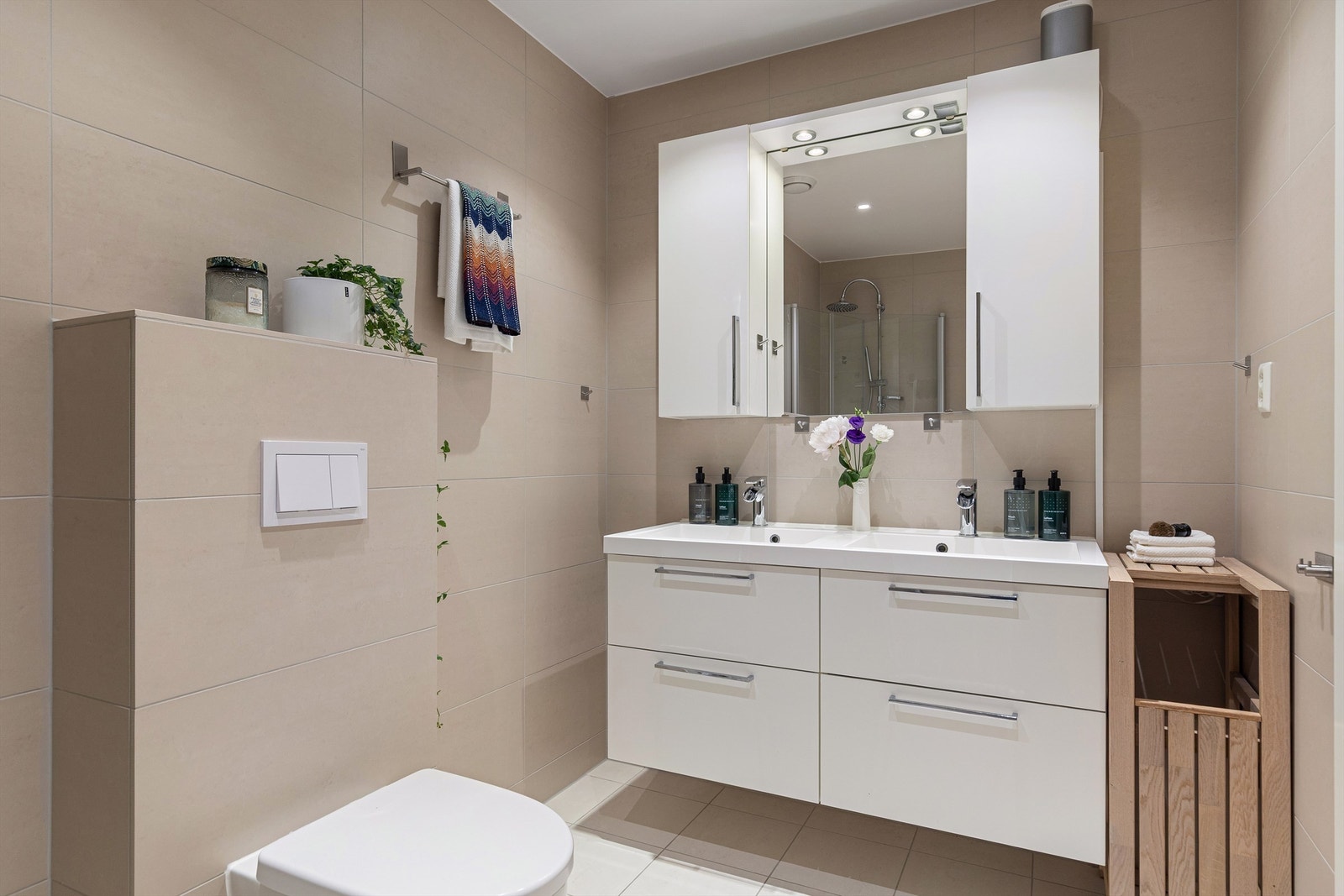 Badet er innredet med vegghengt toalett, dobbelt servant med underliggende skuffer, samt dusjhjørne med innfellbare dusjvegger i glass. Galleribilde