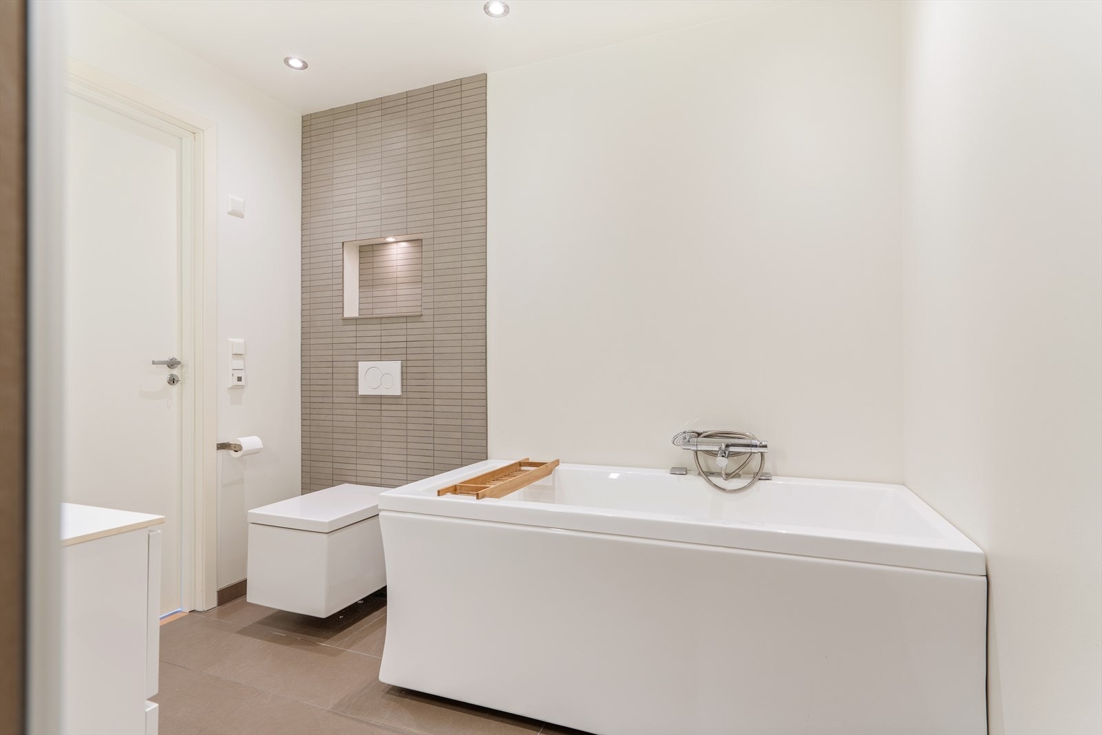 Badet er utstyrt med badekar, veggmontert toalett og varmekabler i gulvet. Galleribilde