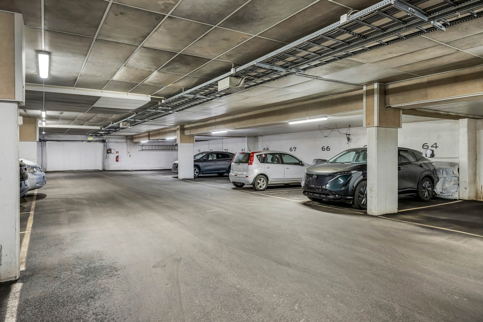 Det medfølger en garasjeplass merket med nr. 64, utstyrt med elbillader for enkel og praktisk lading av elbil. Galleribilde