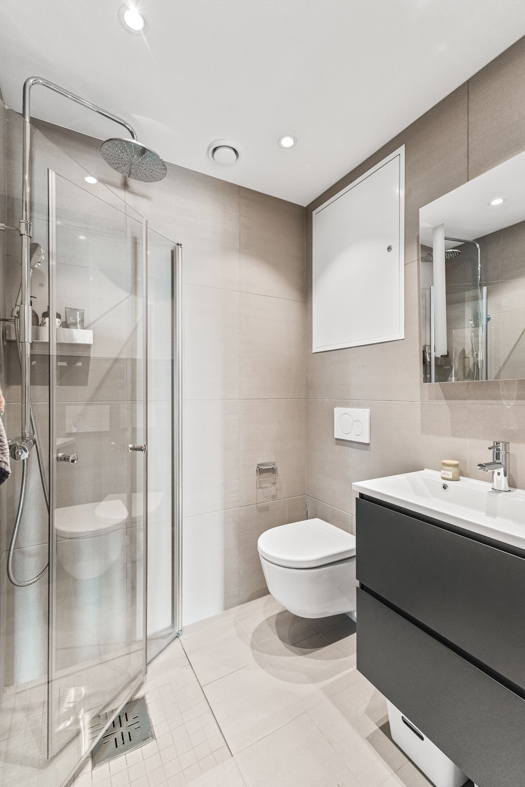 Baderom II er et praktisk og pent flislagt bad fra byggeår med vannbåren varme i gulv. Badet er innredet med servant på underskap, speil, belysning, vegghengt wc og dusj med glassvegger. Galleribilde