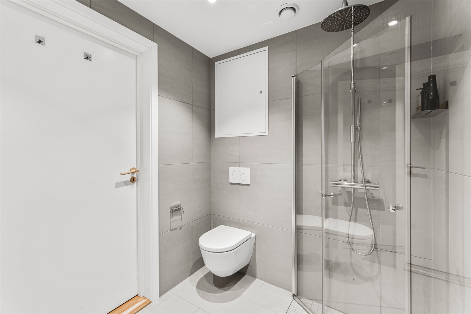 Delikat flislagt hovedbad fra byggeår med vannbåren varme i gulv. Badet er innredet med heldekkende servant på underskap, speil, belysning, vegghengt wc og dusj med glassvegger Galleribilde