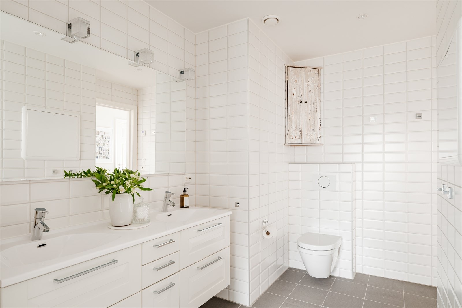 Badet er innredet med vegghengt toalett og en klassisk baderomsinnredning med to servanter, stort speil og gode oppbevaringsmuligheter Galleribilde