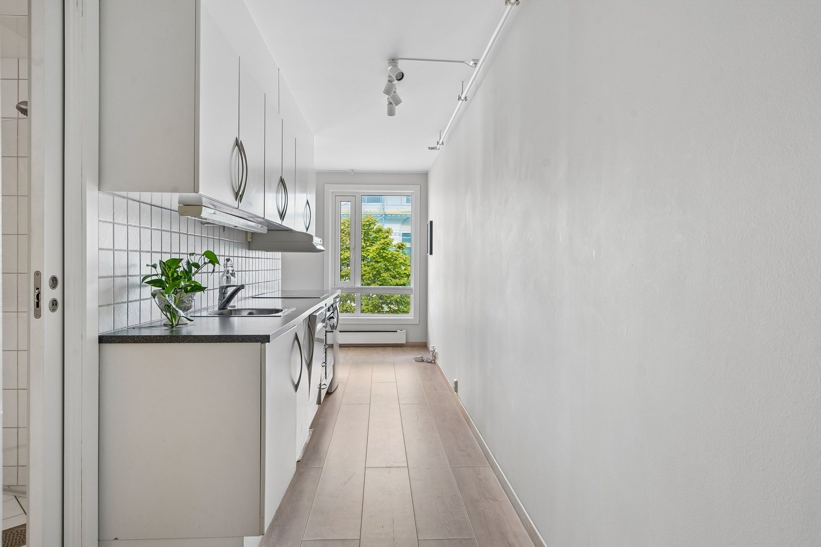 Kjøkkeninnredning med slette fronter, laminat benkeplate og integrert keramisk platetopp og stekeovn. Galleribilde