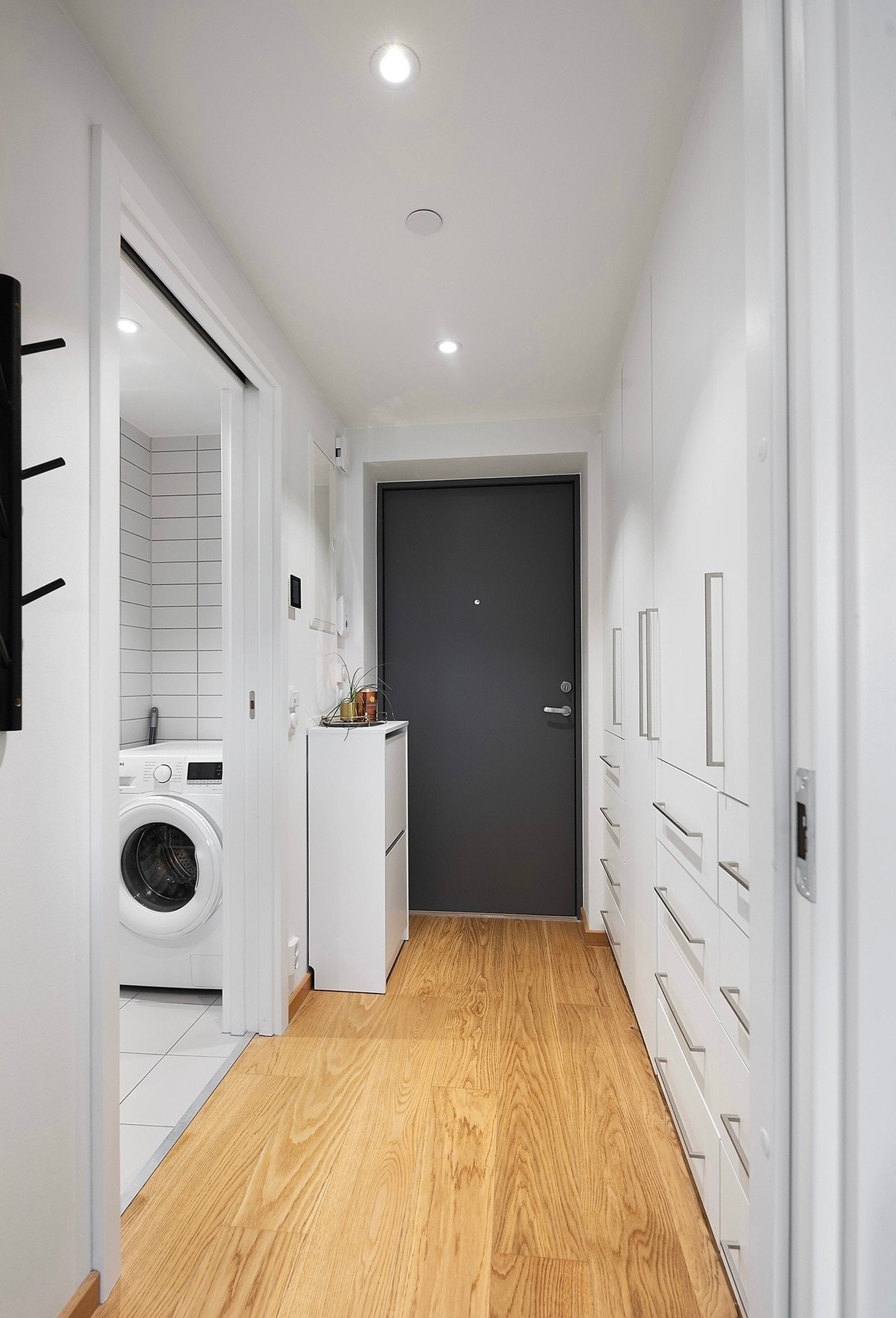 Pen og praktisk entré med hvitmalte vegger, downlights i himlingen og gyllen, enstavs parkett på gulv med vannbåren gulvvarme Galleribilde