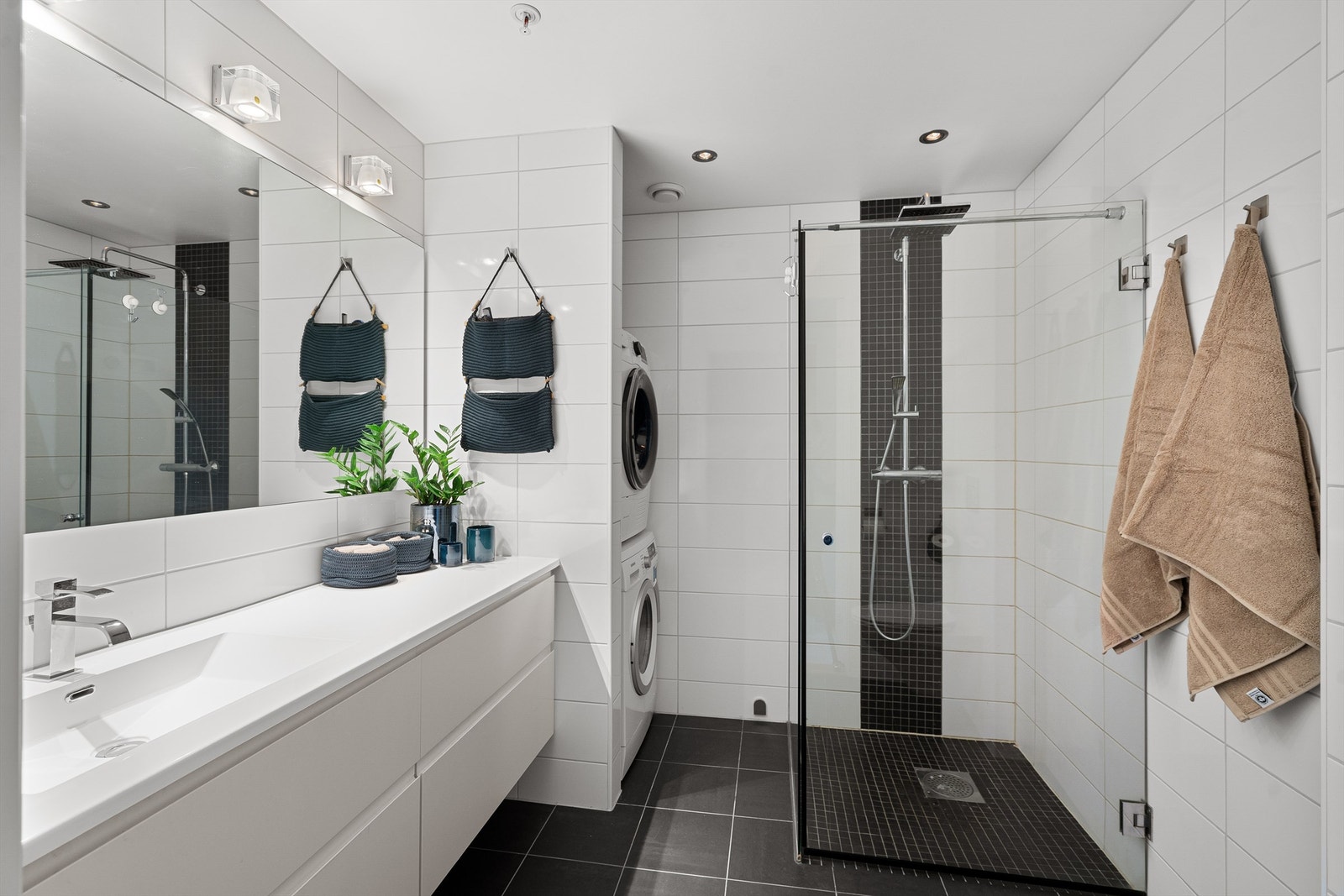 Badet har vannbåren gulvvarme, dusjhjørne med foldbare glassdører og opplegg for vaskemaskin/tørketrommel i nisje. Galleribilde