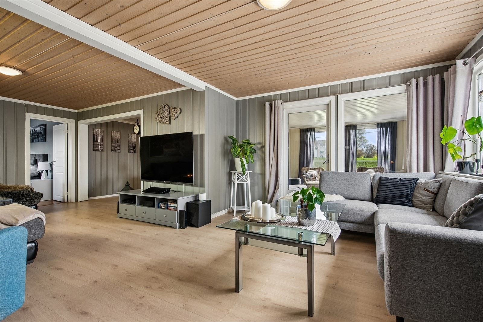 Romslig stue med panel på vegger og i tak, og laminat på gulvet. Galleribilde
