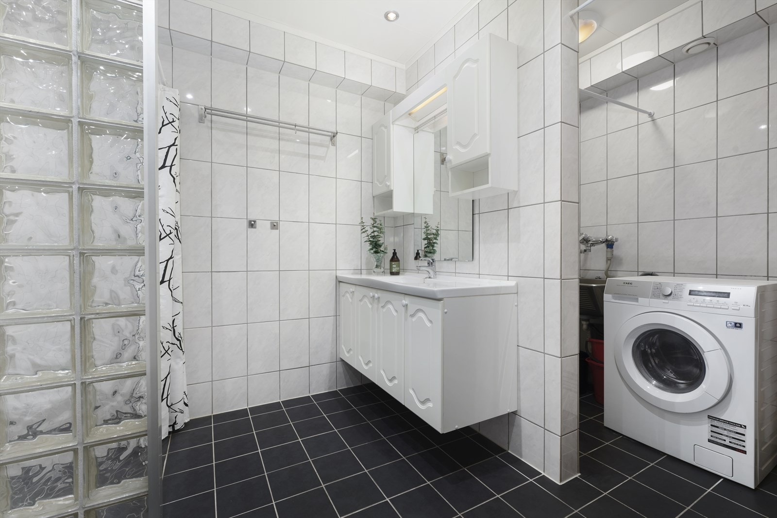 Badet har innredning med nedfelt servant, toalett, dusjvegger/dusjhjørne, utslagsvask og opplegg for vaskemaskin. I tillegg er det montert varmtvannsbereder i rommet. Galleribilde