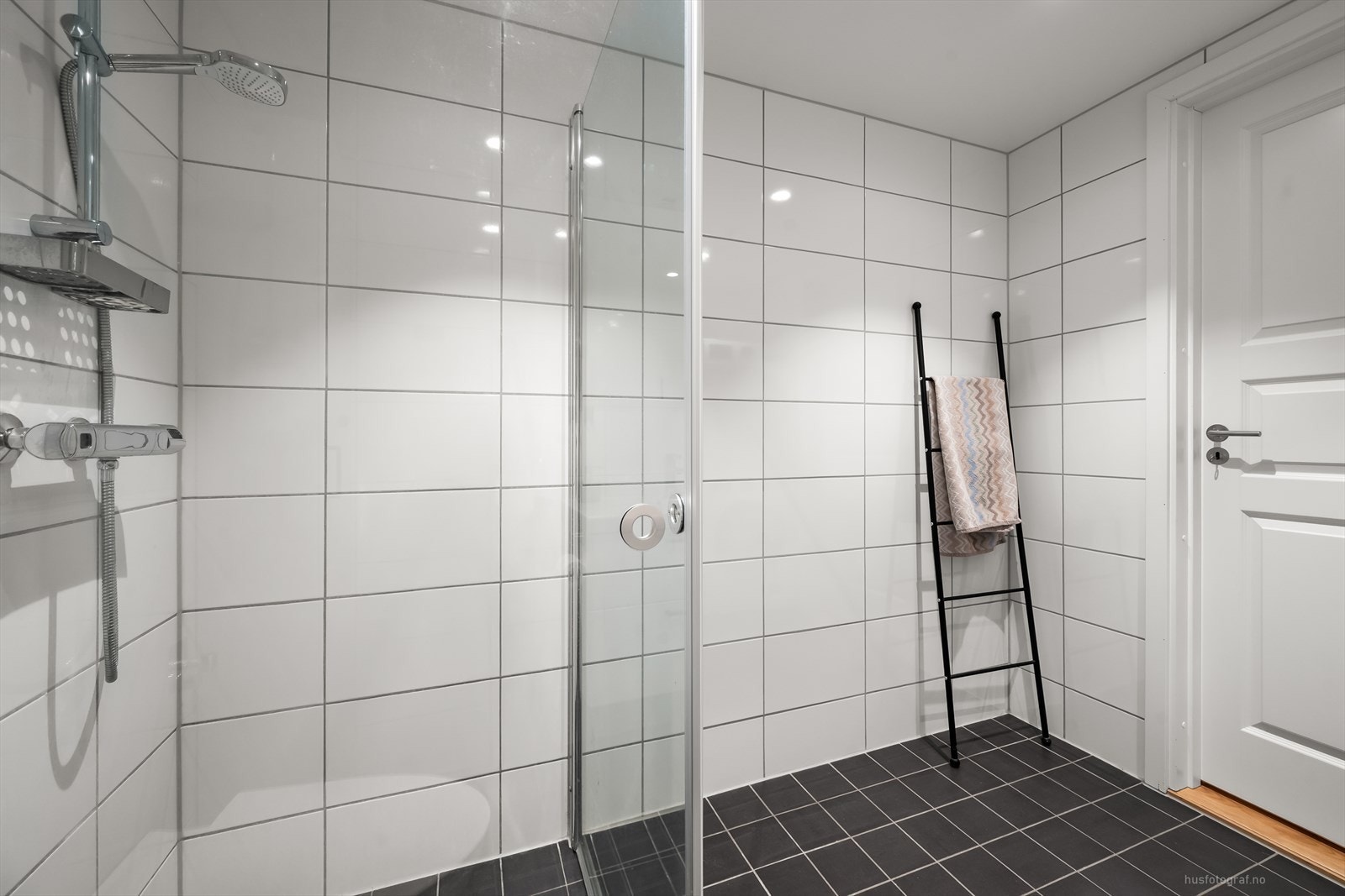 Flislagt bad fra byggeår. Vegger og gulv er tekket med fliser. Himling er tekket med malte flater og innfelte downlights. Elektrisk varme i gulvet. Galleribilde