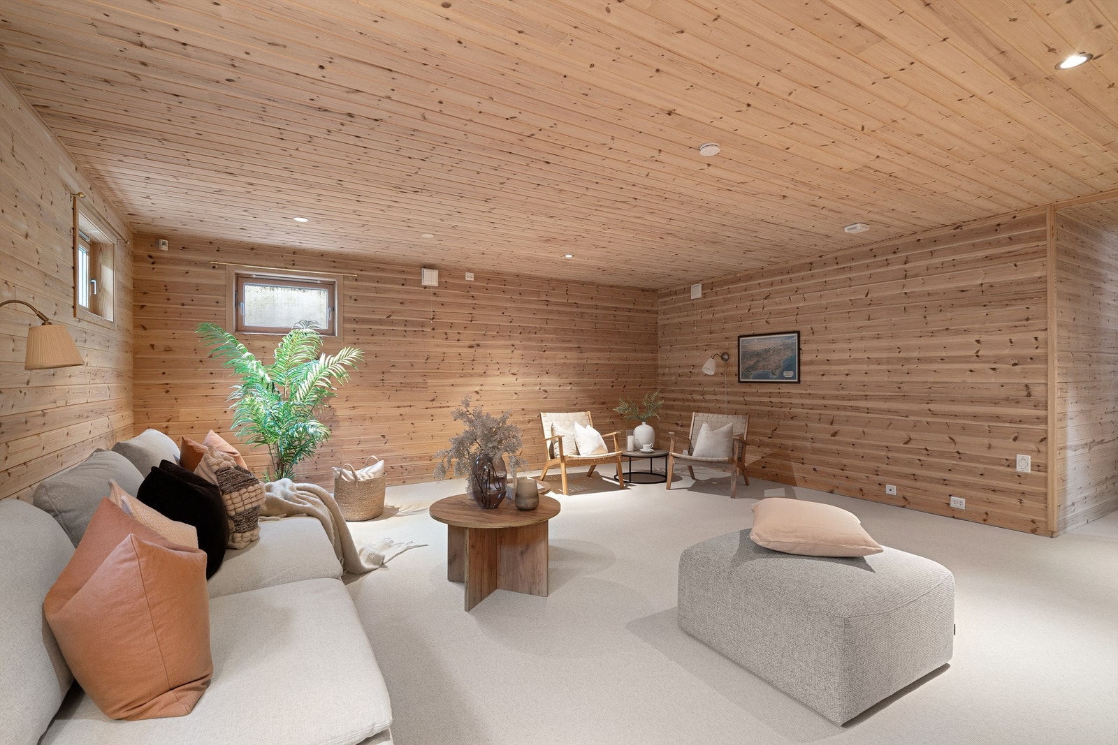 Stor og romslig kjellerstue med nytt teppe på gulv. Det er varmekabler i gulv panel på vegg og tak. Galleribilde