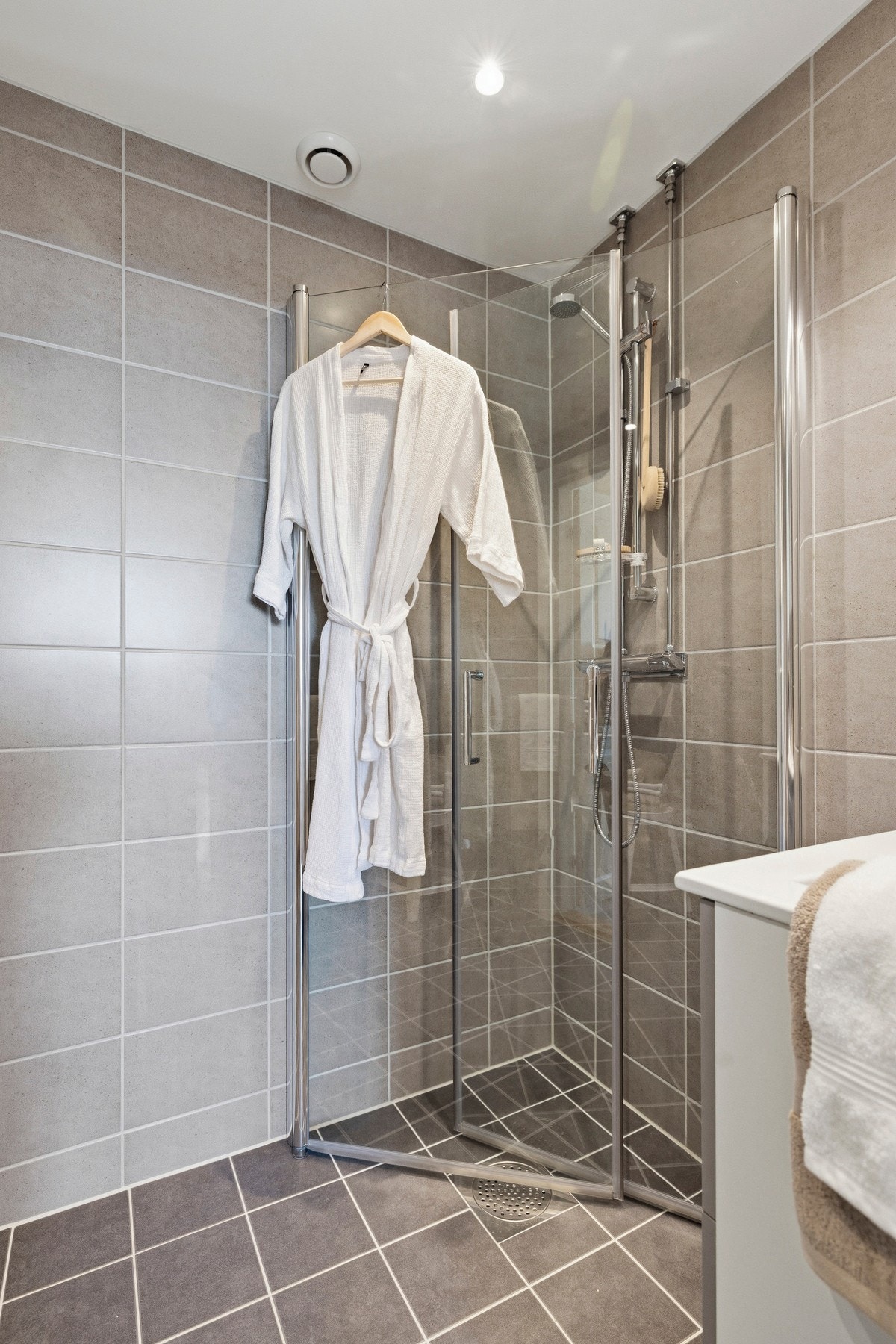 Badet er innredet med skap med glatte fronter, servant og dusj på gulv, samt opplegg for vaskemaskin Galleribilde
