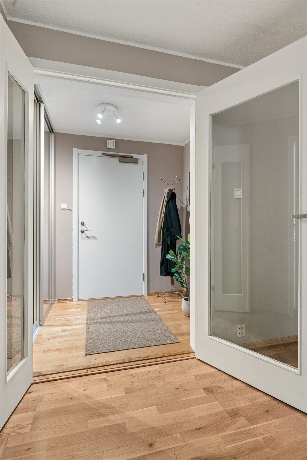 Entréen ønsker velkommen inn i en bolig med gjennomgående parkett på gulv og malte, glatte innerdører. Galleribilde