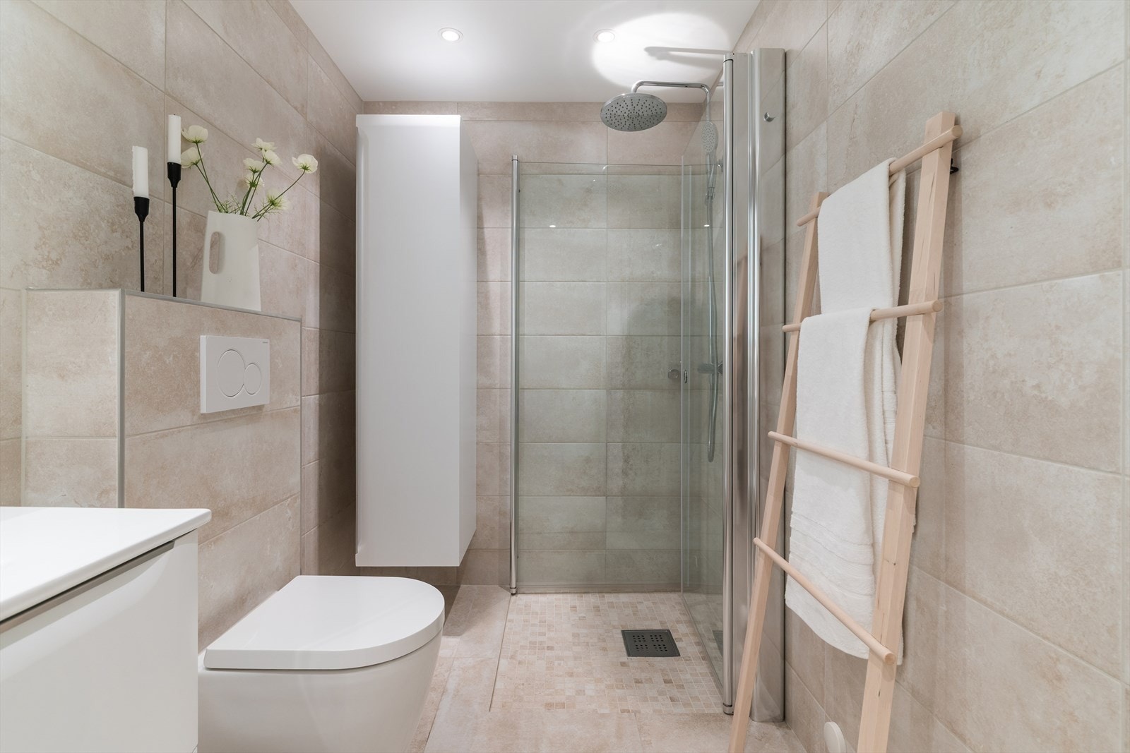 Badet er innredet med dusjhjørne med glassvegger og veggmontert toalett for enklere renhold. Galleribilde