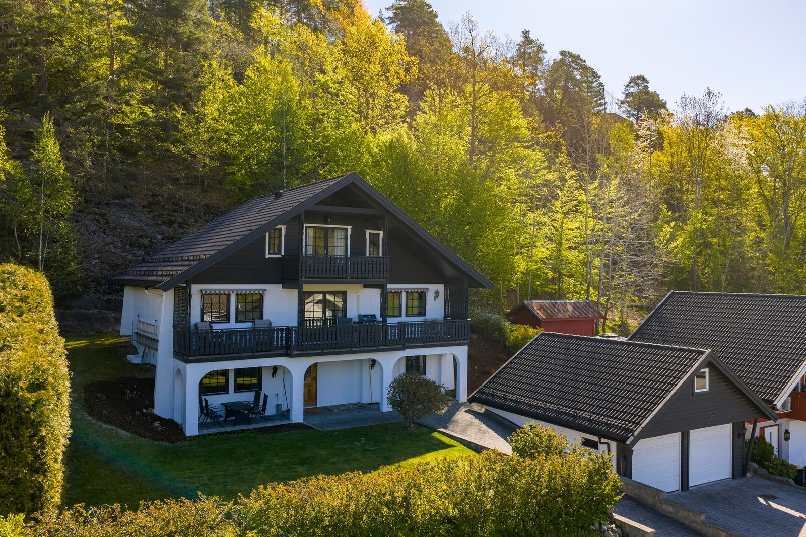 Tomten er opparbeidet med belegningssten på gårdsplass, blomsterbed, plen og hekk Galleribilde
