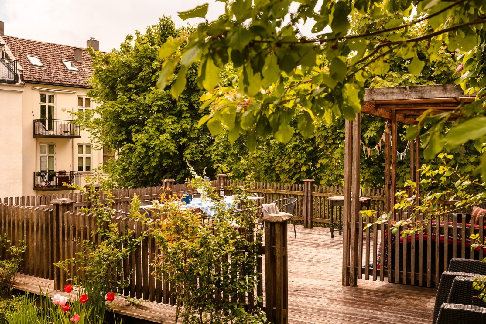 Uteplassen er pent opparbeidet med tredekke og pergola, omgitt av frodig beplantning. Galleribilde