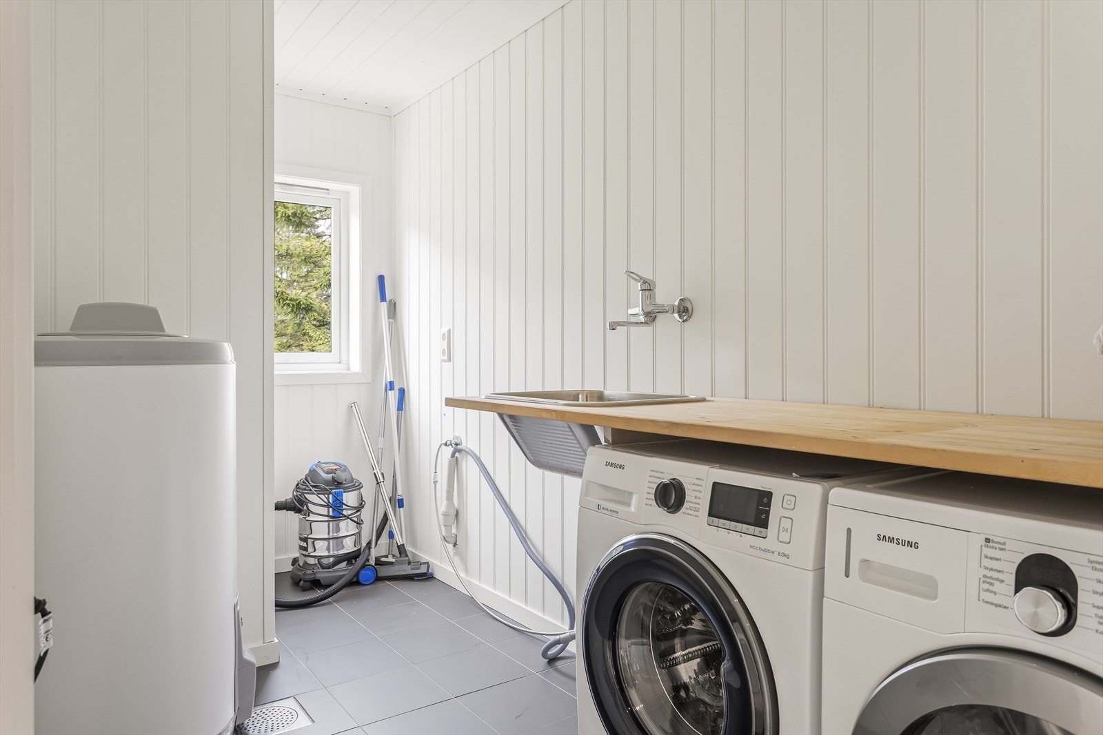 Praktisk vaskerommet med keramiske fliser på gulv, MDF-panel på veggene og malt panel i himling med innfelte spotlights. Vaskerommet ble innredet i perioden ca. 2015-2020 av tidligere eier. Galleribilde