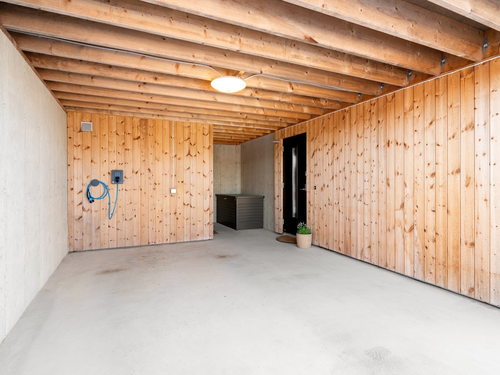 Integrert carport med elbillader og direkte inngang til boligens underetasje. Her er også en praktisk bod. Galleribilde
