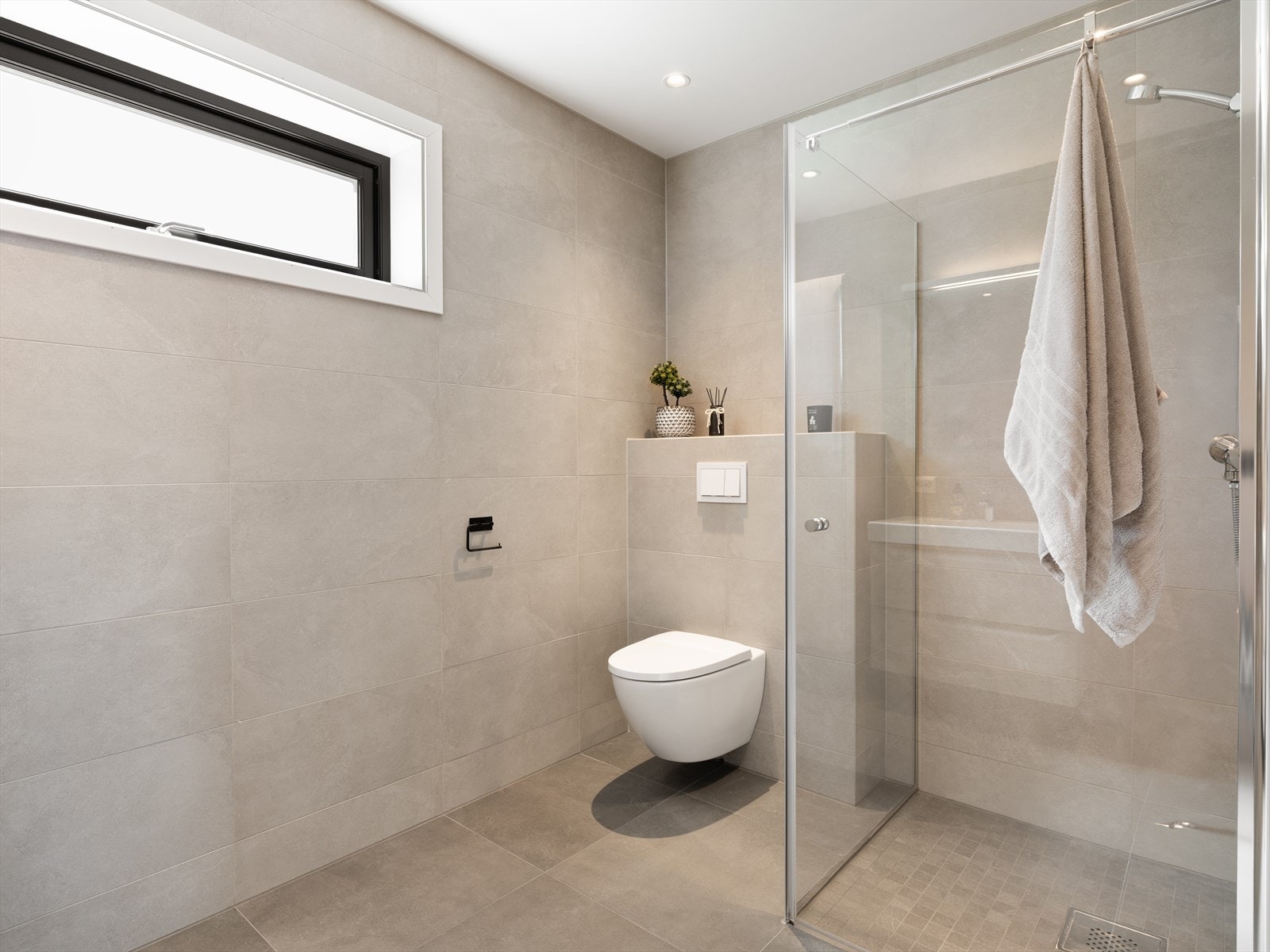 Badet i første etasje har flislagt gulv med varmekabler, vegghengt toalett og dusjhjørne med fast glassvegg og dør som slår inn i dusjen. Galleribilde