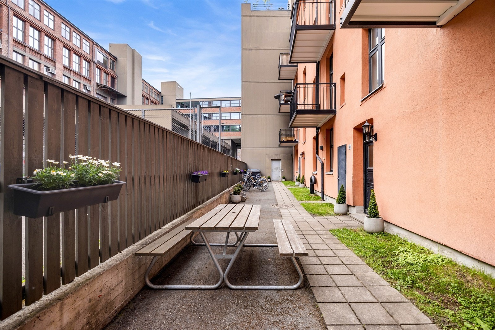 Pent opparbeidet bakgård med diverse beplantning, sykkelparkering og sittegrupper. Galleribilde