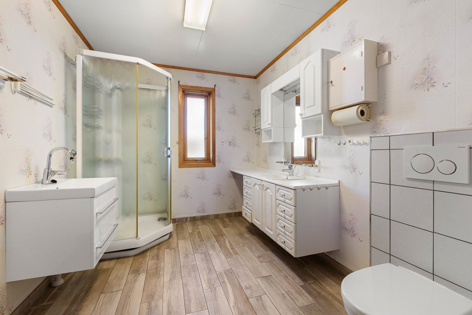Badet ble delvis oppgradert i 2020, blant annet med nye fliser på gulvet, lagt oppå gammelt vinylbelegg. Det er montert nytt
vegghengt toalett og ekstra servant med skap. Galleribilde