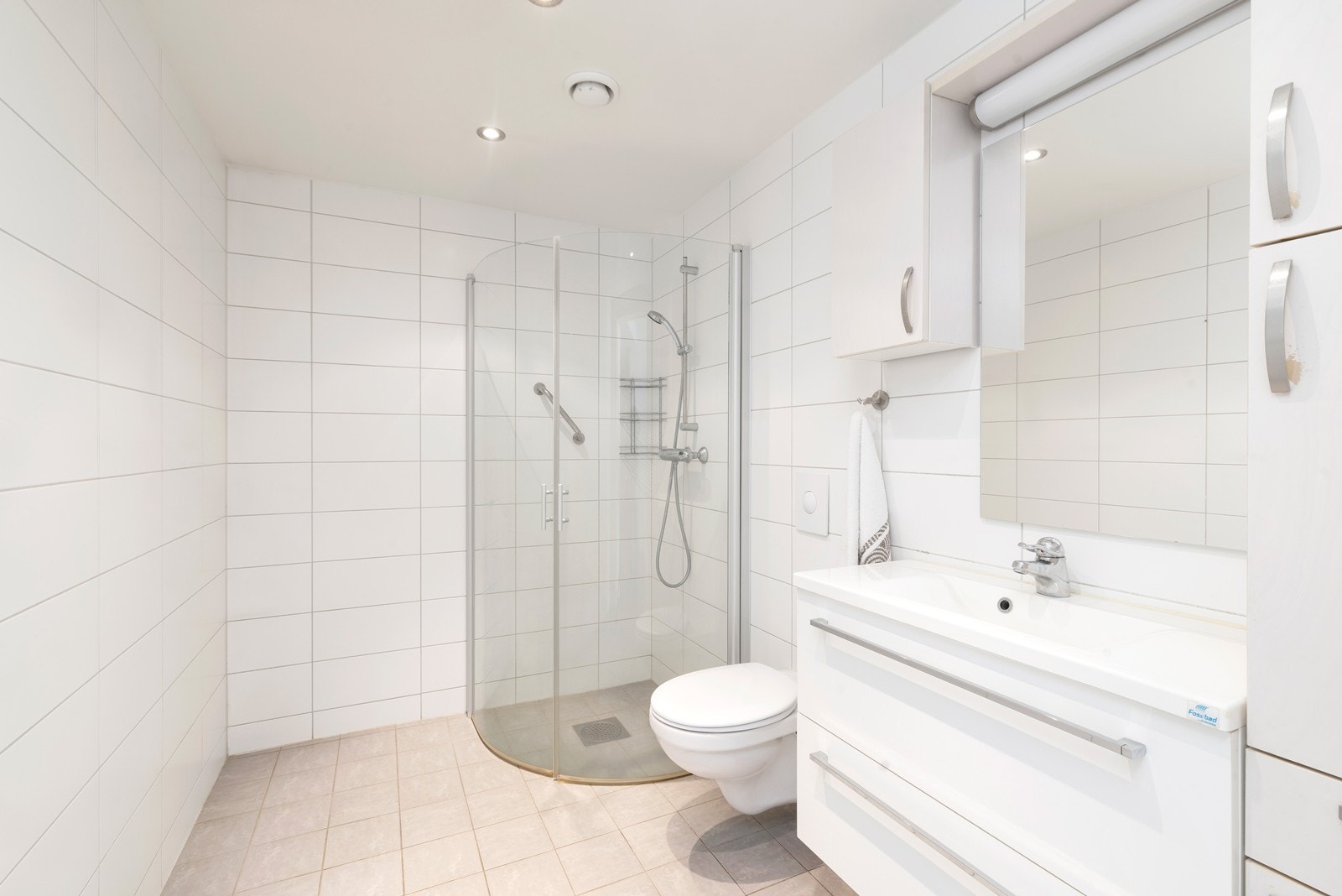 Badet er helfliset med varmekabler. Innredet med servant med skap og speil, toalett og dusj. Galleribilde
