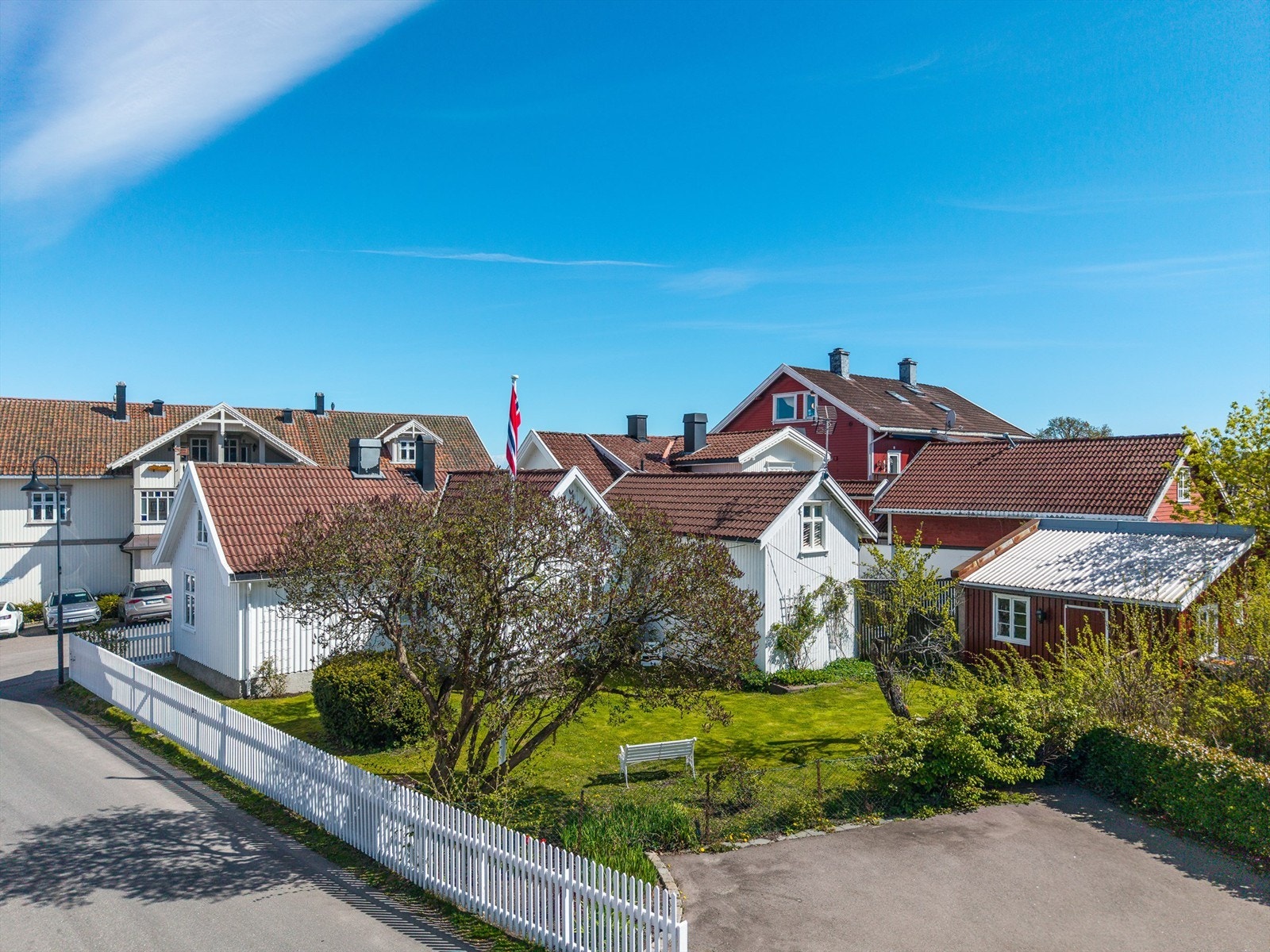 Denne sjarmerende eneboligen fra midten av 1700-tallet er rammet inn av et hvitt stakittgjerde. Innenfor ligger en idyllisk hage med bla. flaggstang og bryggerhus.
Foto: Fotofinish AS v/Kristian Bollæren Galleribilde