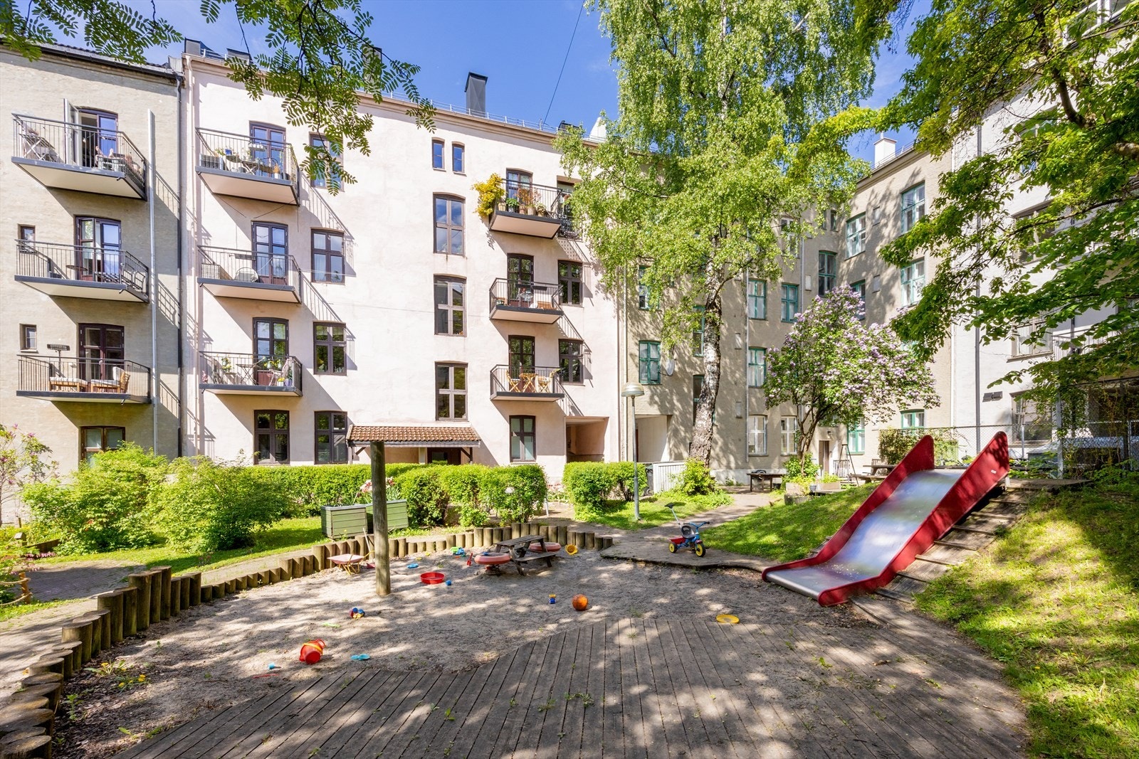 Den idylliske bakgården er en skjermet oase med beplantning, sittegrupper og lekeplass, tilbaketrukket fra bylivet. Galleribilde
