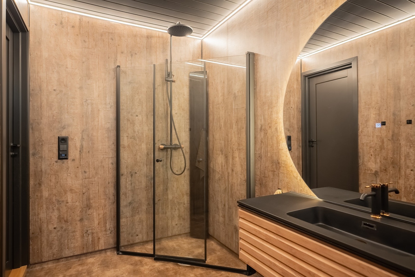 Badet er utstyrt med dusjvegger av glass, vegghengt toalett, og servant med underskap. Galleribilde