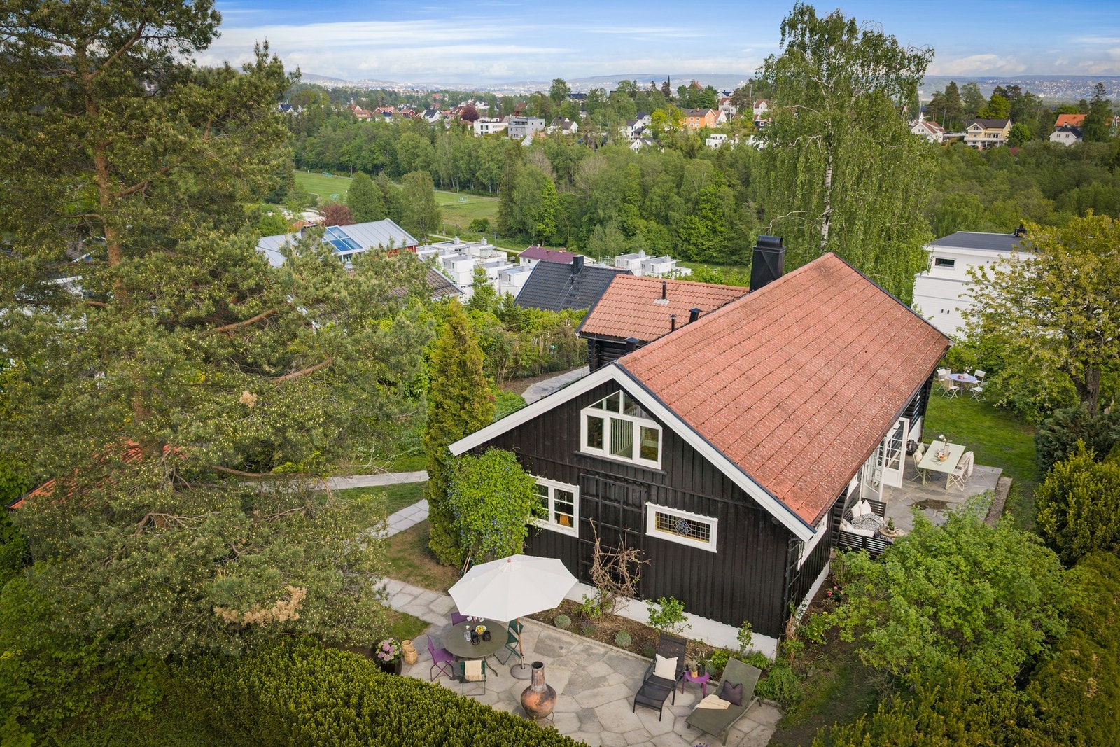 Huset oppleves usjenert, beliggende på en høyde og da tomten er opparbeidet med trær, busker og beplantning Galleribilde