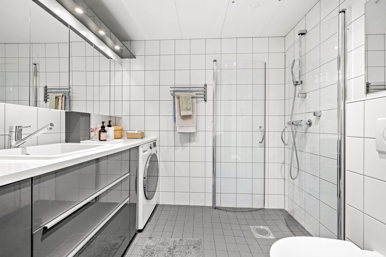 Lyst og innbydende bad med varmekabler i gulv og downlights i himling. Servant, toalett, dusjdører og innredning ble oppgradert i 2013. Galleribilde