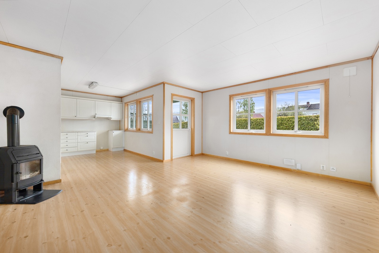 Den åpne løsningen mellom stue og kjøkken skaper et sosialt og luftig allrom, og vedovnen gir lun og effektiv varme. Galleribilde