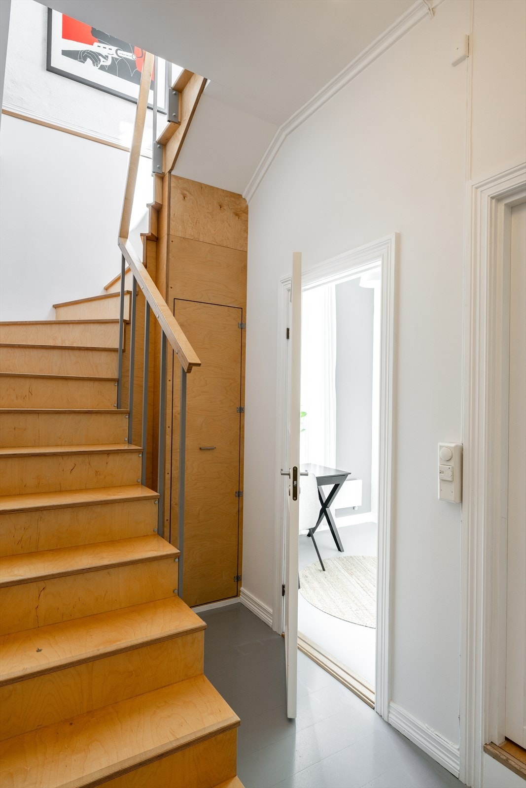 Det åpne og luftige trapperommet binder etasjene sammen på elegant vis. Under trappen er det etablert praktiske oppbevaringsmuligheter som utnytter arealet på en smart måte. Galleribilde