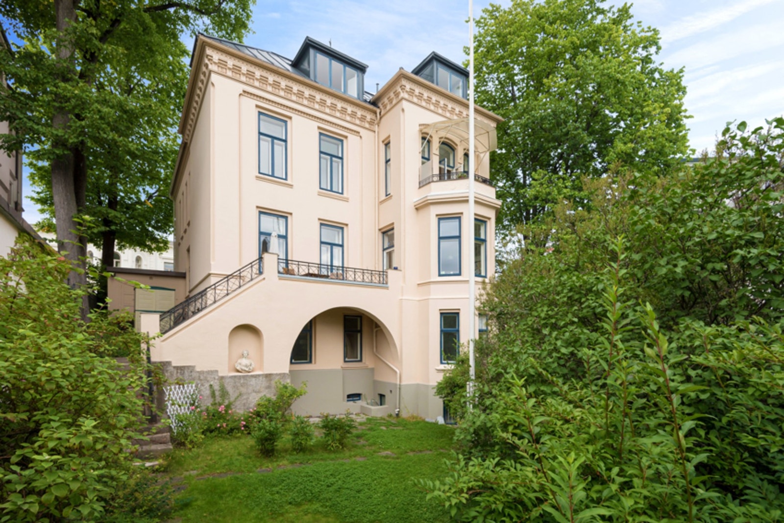 Mot hagesiden åpner eiendommen seg med karnapp, terrasser og grøntarealer som gir stedet en nærmest kontinental tilnærming. Galleribilde