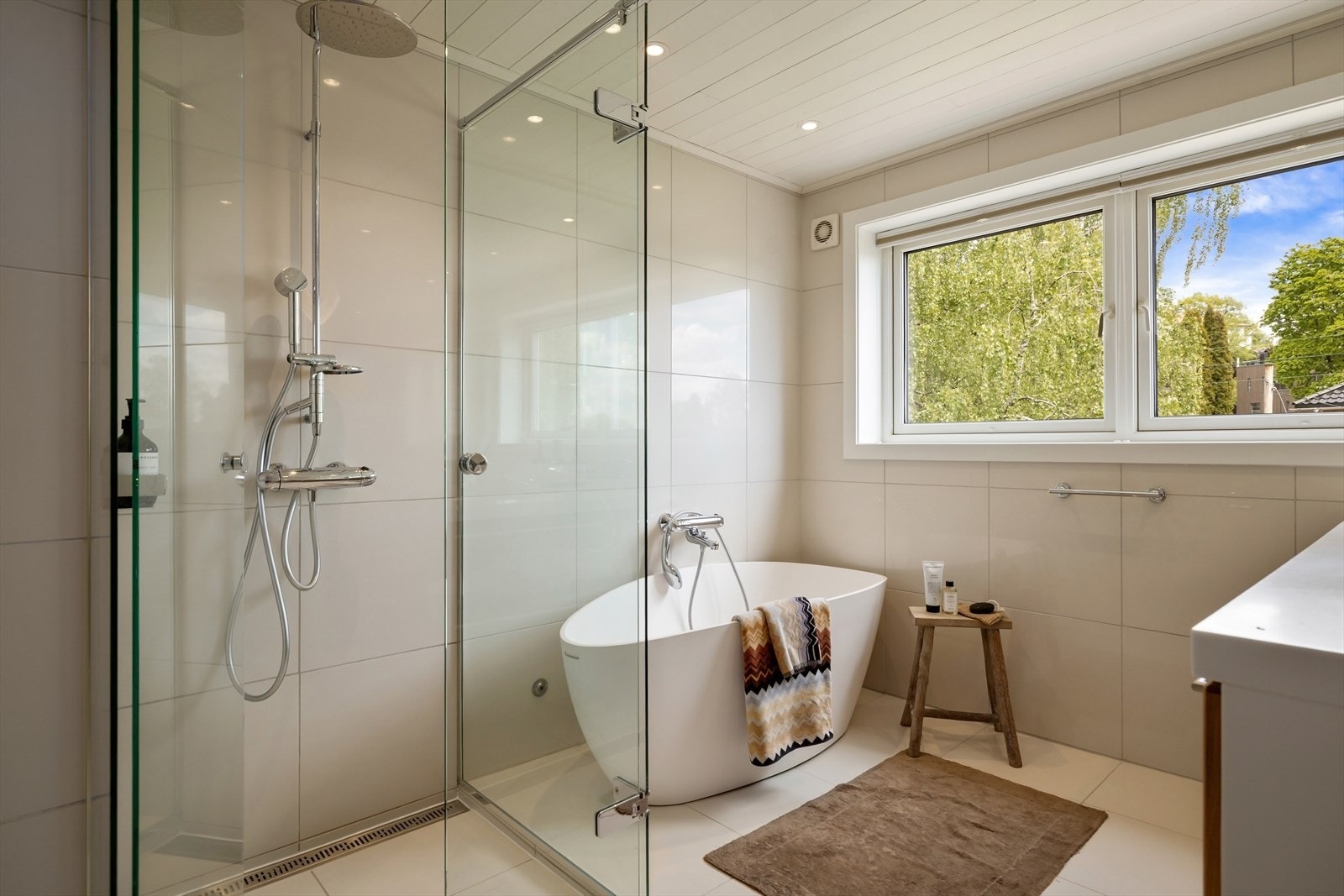 Badet har flislagt gulv, panel i taket med downlights og en elektrisk styrt vifte. Galleribilde