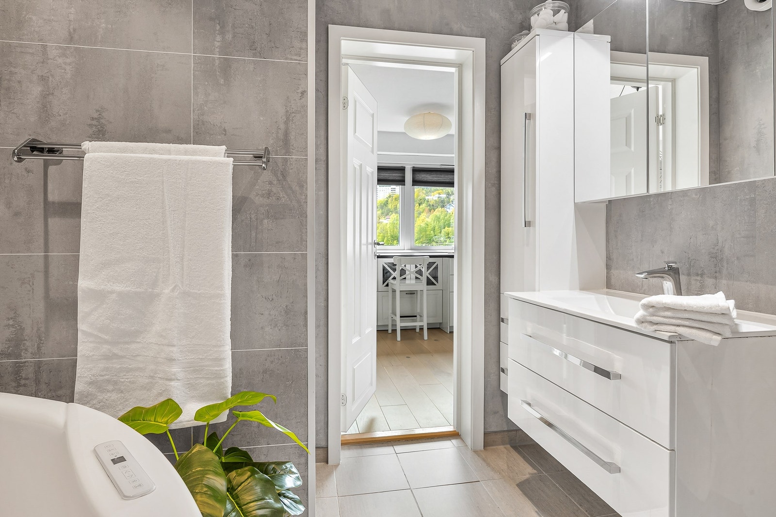 Badet er innredet med vegghengt servantinnredning, speilskap med overlys og vegghengt baderomsmøbel for ekstra oppbevaring. Galleribilde