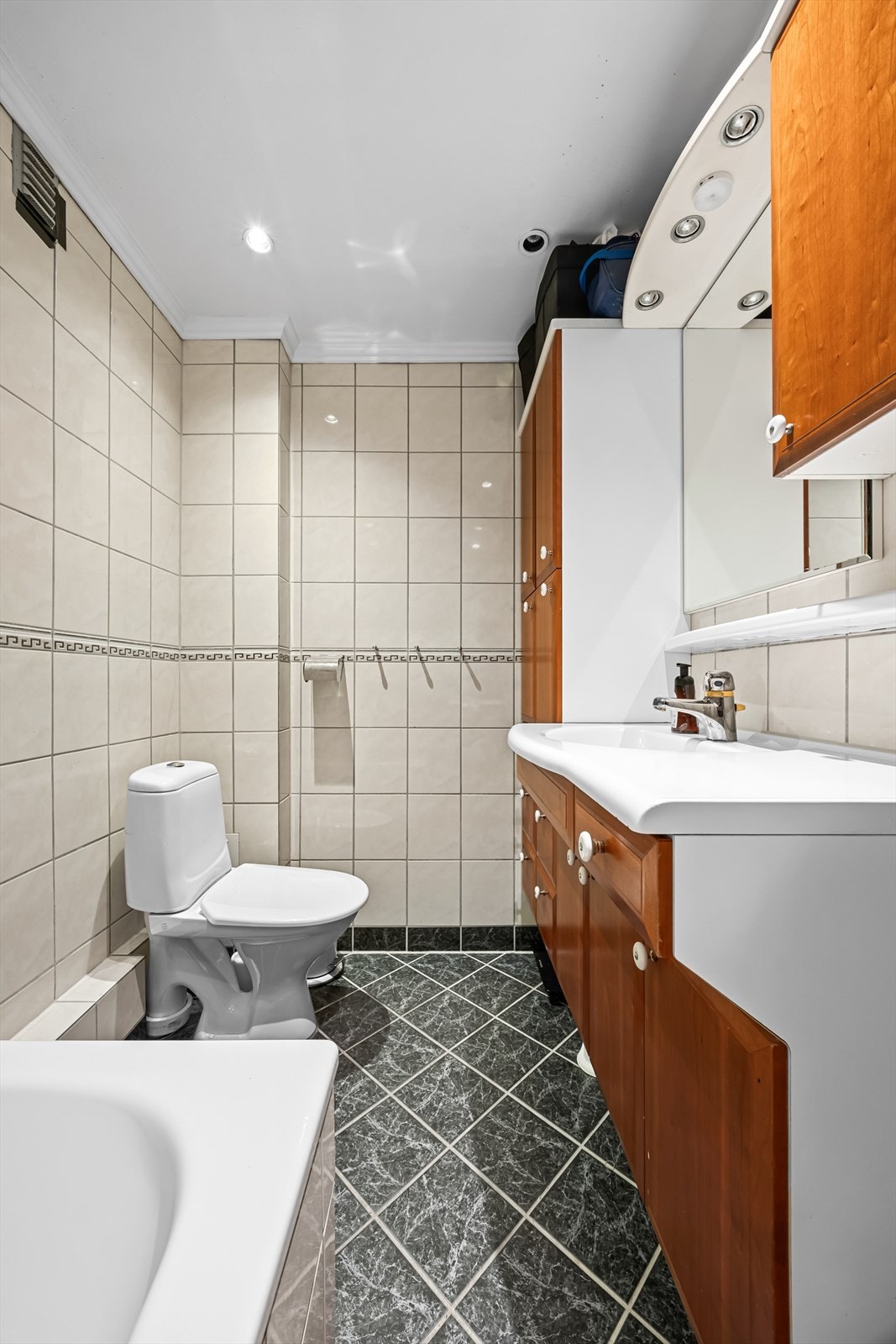 Badet er innredet med servantskap med ett-greps blandebatteri, gulvstående toalett, badekar samt dusjgarnityr. Galleribilde