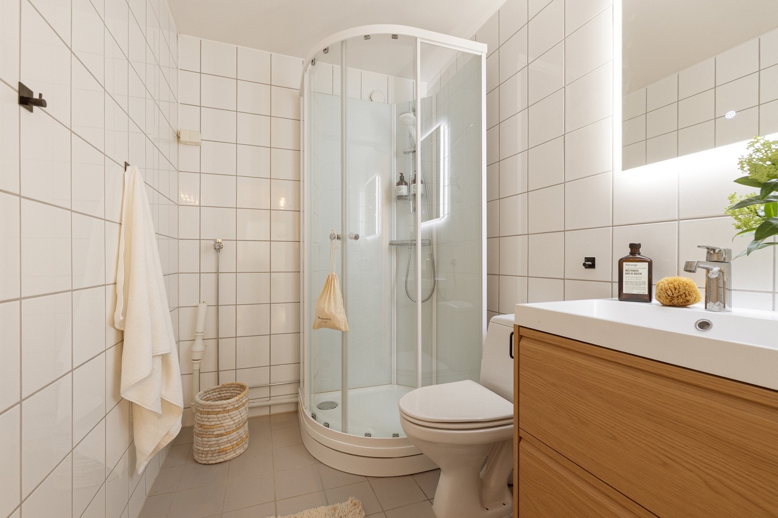 Badet er innredet med servant med underskuffer, moderne speil med belysning, dusjkabitnett og toalett. Det er videre opplegg for vaskemaskin. Galleribilde