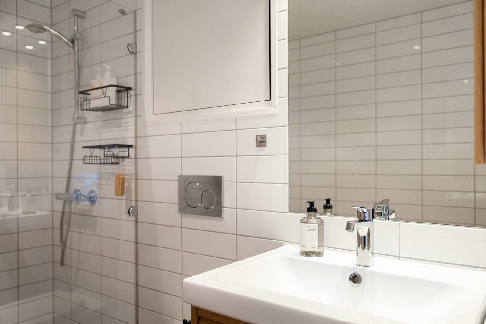 Badet er innredet med vegghengt klosett, servant med innredning, innfelt speil og dusjhjørne med glassdør. Galleribilde