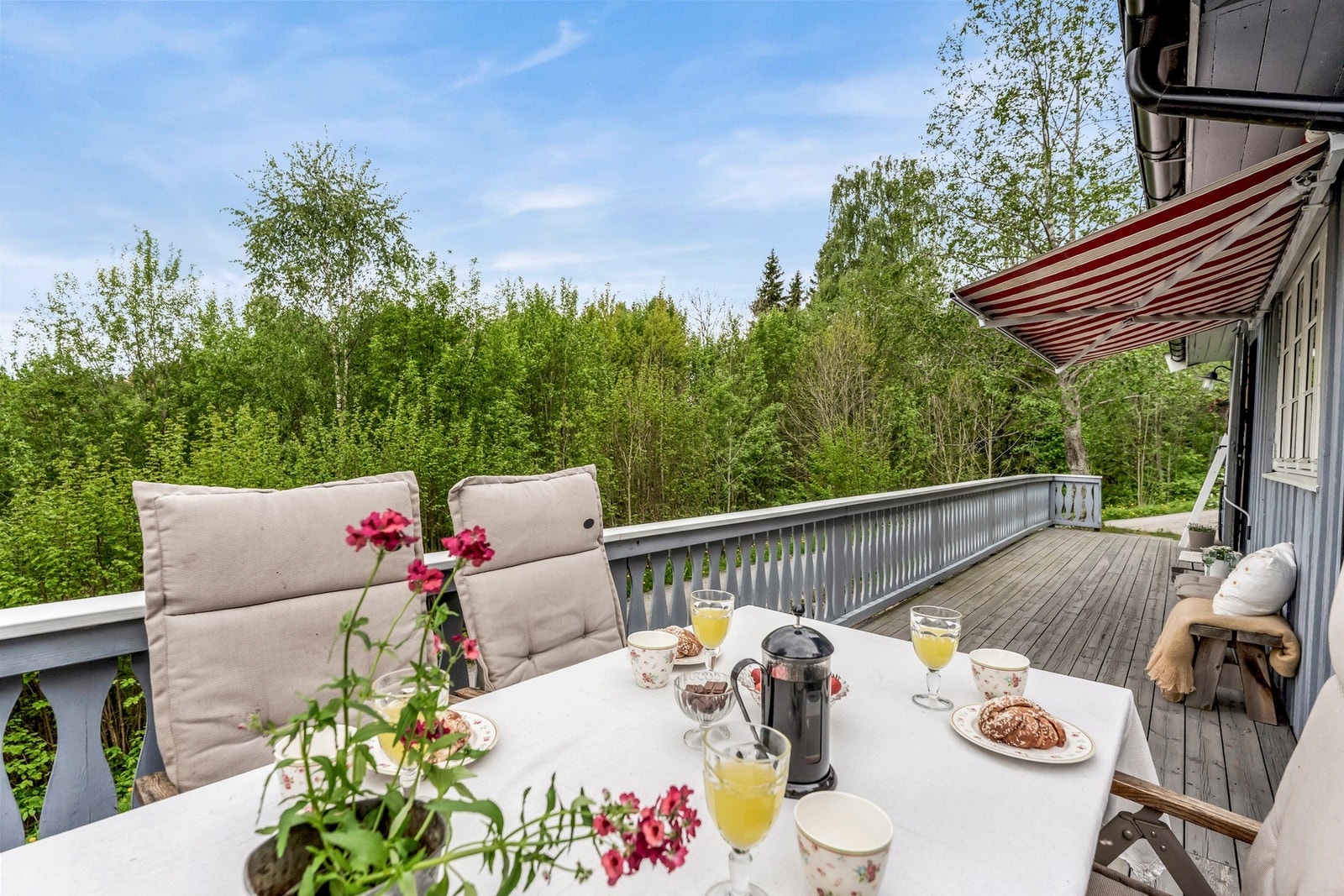 Romslig terrasse med markise, omgitt av frodig natur. Galleribilde